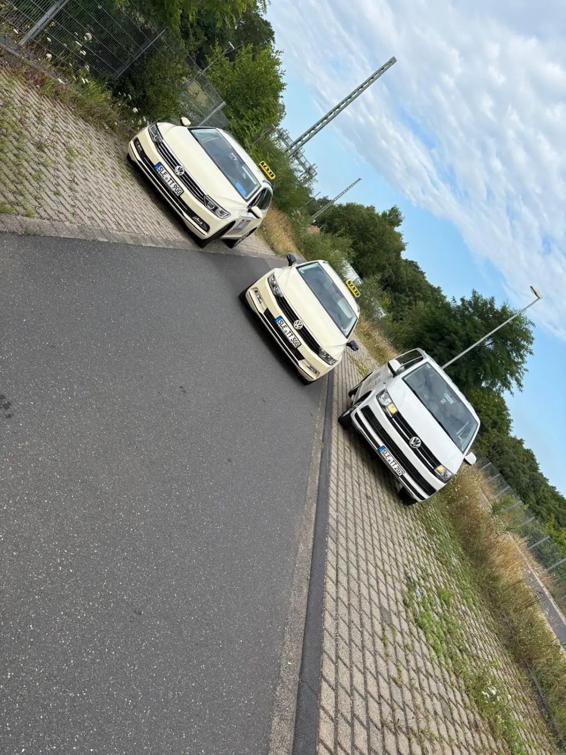 BonChance & TaxiTopTeam GmbH - Transportdienste - Ein weißer, rollstuhlgerecht umgebauter VW-Bus parkt auf der Straße. Die Heckklappe ist geöffnet, und eine Metallrampe ist zum Gehweg ausgeklappt.